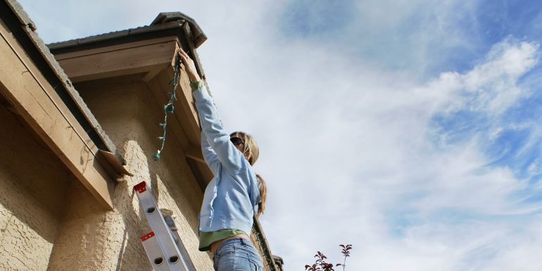 Kobieta wiesza lampki świąteczne